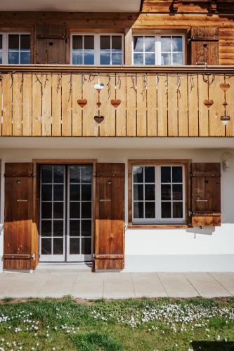 a house with wooden doors and a balcony at Hidden Retreats The Signature in Brienzwiler