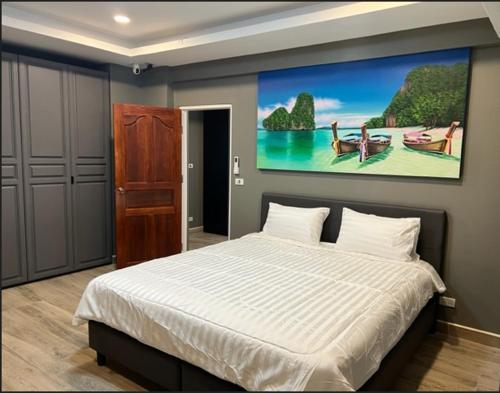 a bedroom with a bed with a painting on the wall at Patong Vacation Rentals - Located in the Heart of Patong, Studio Apartments walking distance to the beach, King Bed, Kitchen, Private Bathroom, Seating Area, 65" Smart TV with Free WIFI in Patong Beach