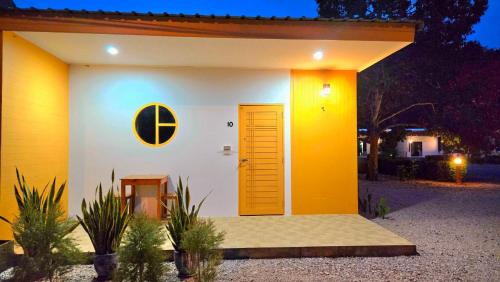 a small house with a yellow door in a yard at Suanvadee Resort สวนวดี รีสอร์ท in Don Sak