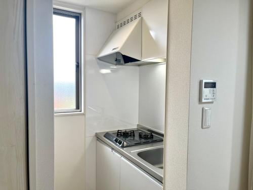 a white kitchen with a stove and a sink at とすアジュール in Tosu