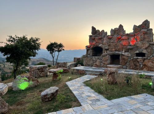 an old stone building with a bench in a field at Guest House Novaku 