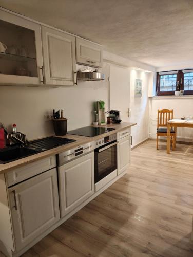a kitchen with white cabinets and a wooden floor at Ferienunterkunft in Fuldabrück