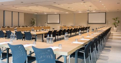 a large conference room with long tables and chairs at Crowne Plaza Utrecht - Central Station by IHG in Utrecht