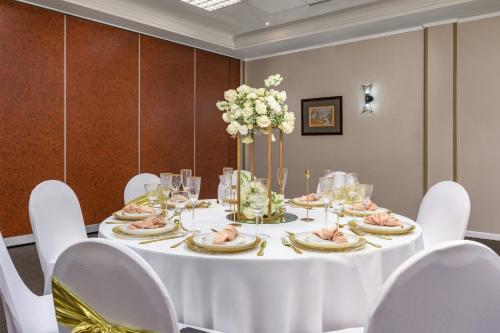 a table with white chairs and a white table with food on it at Protea Hotel by Marriott Karridene Beach in Amanzimtoti