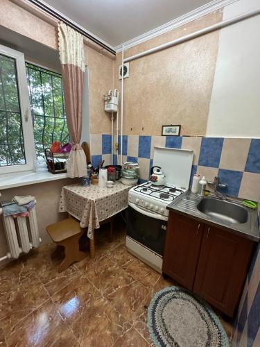 a kitchen with a stove and a sink and a table at Парковая 18, первая линия от моря in Chornomorsk