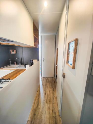 a kitchen with white walls and a wooden floor at Mobilhome 6p camping le bois dormant in Quend-Plage