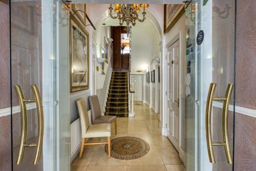 a hallway with a staircase and a chandelier at Opulence Boutique Hotel in London