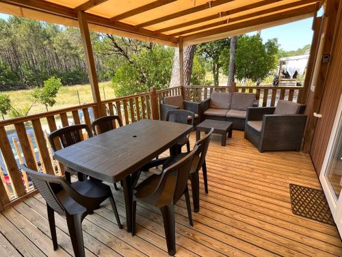 une terrasse en bois avec une table et des chaises en bois dans l'établissement Mobilhome 7 personnes climatisé - Camping 4 étoiles, à Lège-Cap-Ferret