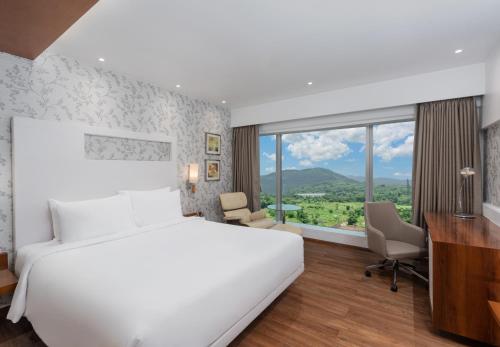 a bedroom with a large white bed and a desk at Country Inn & Suites By Radisson Navi Mumbai in Navi Mumbai