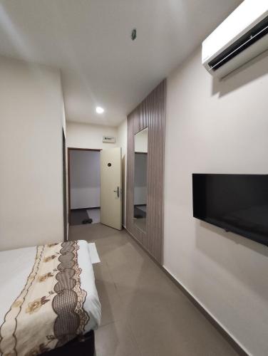a bedroom with a bed and a flat screen tv at Mass Hotel in Kampong Kerayong
