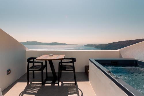 a balcony with a table and chairs and a swimming pool at Cavo Tagoo Santorini in Imerovigli