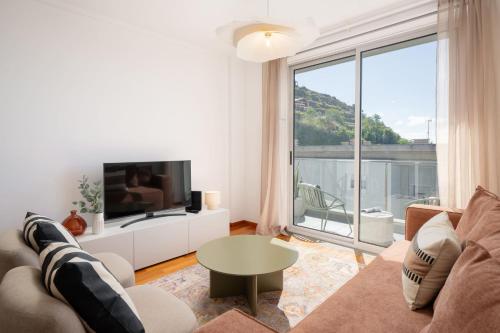 een woonkamer met een bank en een groot raam bij Wings Apartment II by An Island Apart in Santa Cruz