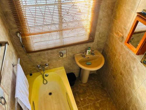 a bathroom with a yellow tub and a sink at Konayethu BnB in Mdantsane