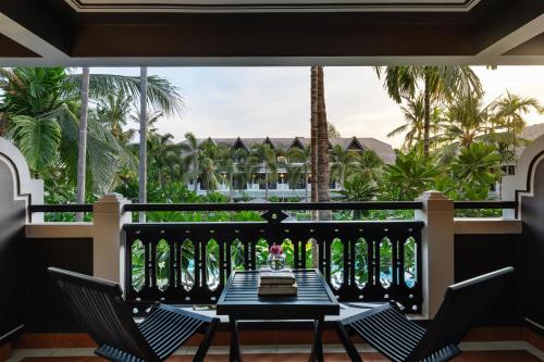 a balcony with a table and chairs and palm trees at Shinta Mani Angkor in Siem Reap