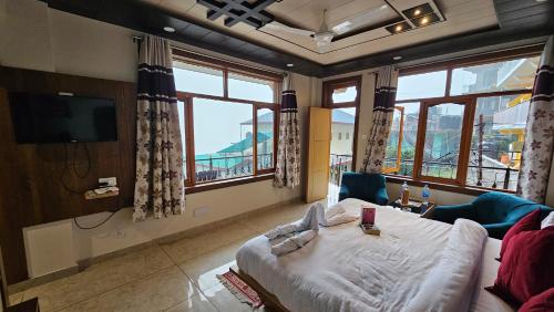a bedroom with a bed and a tv and windows at Hotel Green View McLeod Ganj in Dharmsala