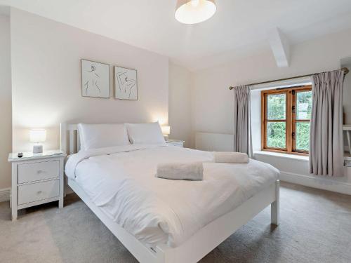 a white bedroom with a large white bed and a window at 4 Bed in Berrynarbor 95899 in Berrynarbor