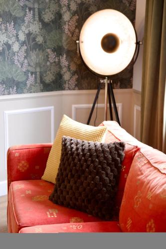 a lamp sitting next to a red couch with a pillow at Le Familia in Guer
