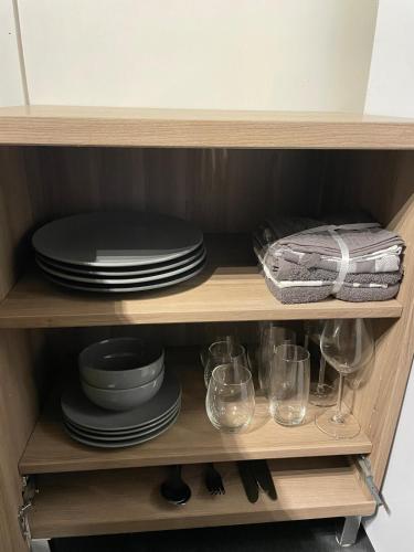 a cabinet with plates and glasses on a shelf at Cozy Studio in the heart of the village in Hippolytushoef