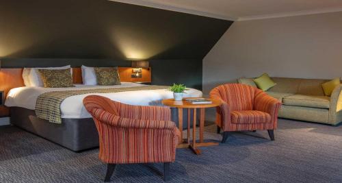 a hotel room with a bed and a table and chairs at Best Western Plus Angel Hotel in Chippenham