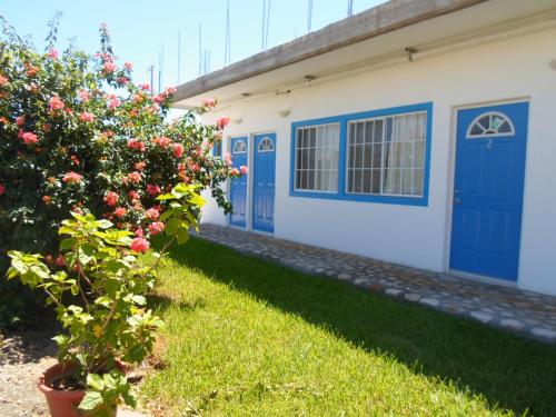 a house with blue doors and a bush with flowers at Hotel y Suites Del Paci­fico in Salina Cruz