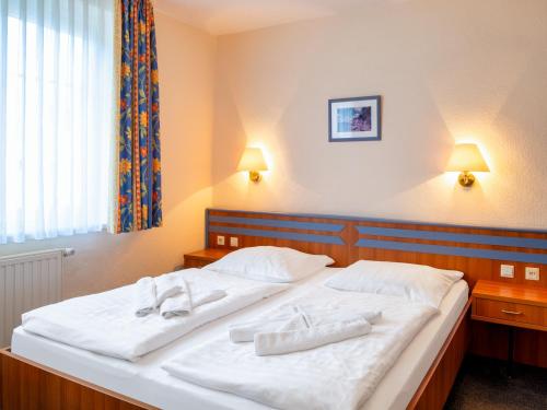 a bedroom with a large white bed with two white towels at Hotel Selliner Hof in Ostseebad Sellin