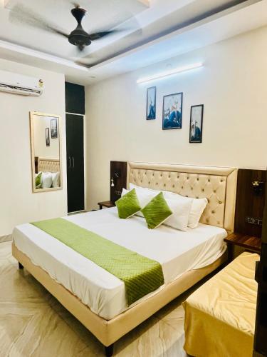 a bedroom with a large white bed with green pillows at Hotel Heaven in Rohtak