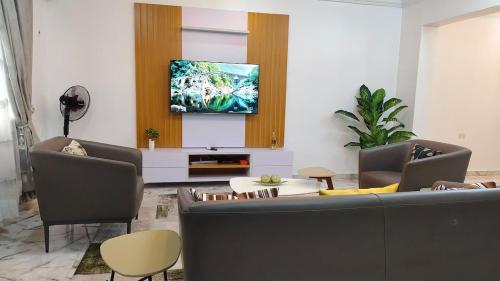 a living room with a couch and a tv on a wall at Keev Homes 2 bedroom Apartment in Port Harcourt