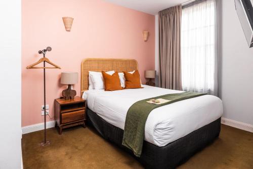 a bedroom with a large bed with orange pillows at The Lucky Hotel in Newcastle