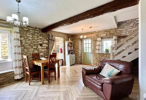 a living room with a table and a leather couch at Bilsdale Cottage in Helmsley
