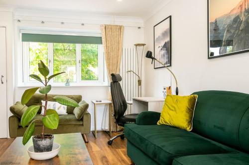 a living room with a green couch and a chair at Cherry Tree Cottage in Bicester