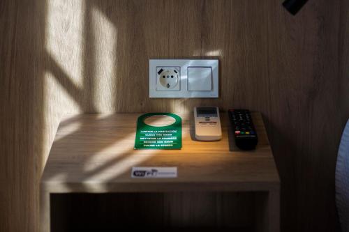 a table with a phone and a remote control on it at Pensión Dulces Sueños in Seville