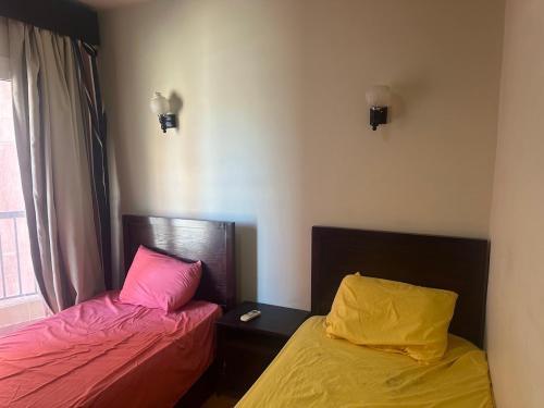 two beds in a room with pink and yellow sheets at Golf Porto Marina VIP in El Alamein