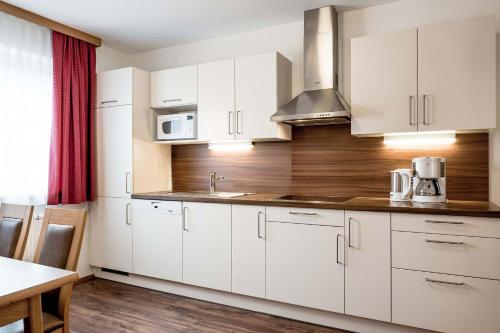 a white kitchen with white cabinets and a table at DIE BARBARA Appartements & Zimmer in Schladming