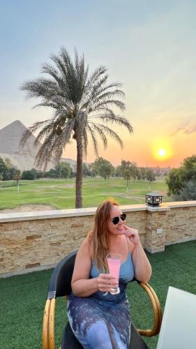 a woman sitting in a chair with a drink at New Jazal pyramids view in Cairo