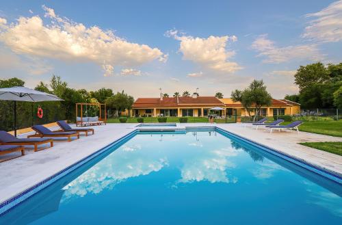 a swimming pool with chairs and a house at Quinta da Corticeira in Elvas