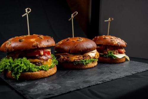 three hamburgers sitting on a table with tooth picks in them at AllEia rooms in Sebeş
