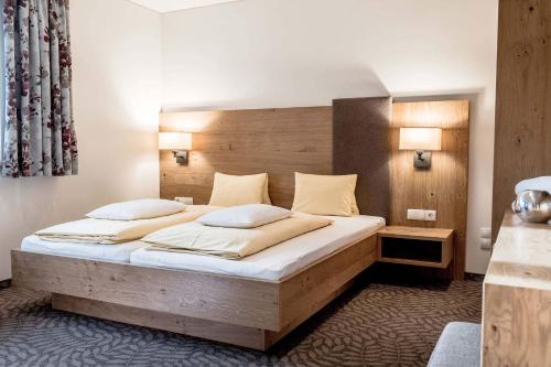 a bedroom with a large wooden bed with two pillows at DIE BARBARA Appartements & Zimmer in Schladming