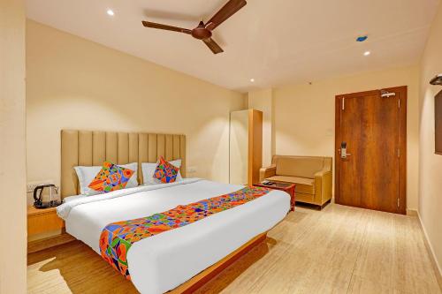 a bedroom with a large bed and a chair at FabHotel Siddarth in Vijayawāda