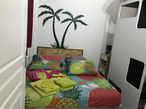a bedroom with a bed with a palm tree on the wall at Maison en résidence privée avec piscine accès plage in Les Trois-Îlets