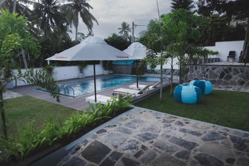 a resort pool with an umbrella and inflatables at Travel Cage in Hikkaduwa