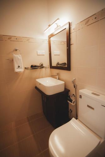 a bathroom with a toilet and a sink and a mirror at Travel Cage in Hikkaduwa