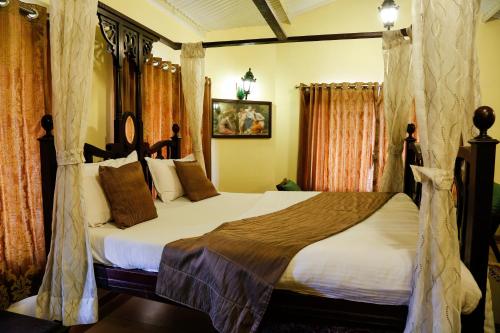 a bedroom with a large bed with curtains and a canopy at The Colonial Manek Manor By SAH in Mount Ābu