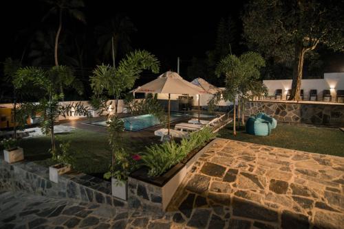 a backyard at night with a pool and an umbrella at Travel Cage in Hikkaduwa