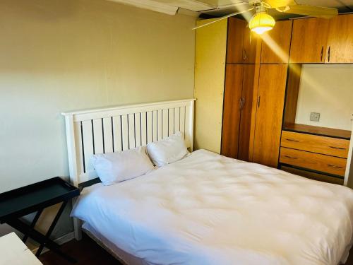a bedroom with a large white bed and a dresser at Konayethu BnB in Mdantsane