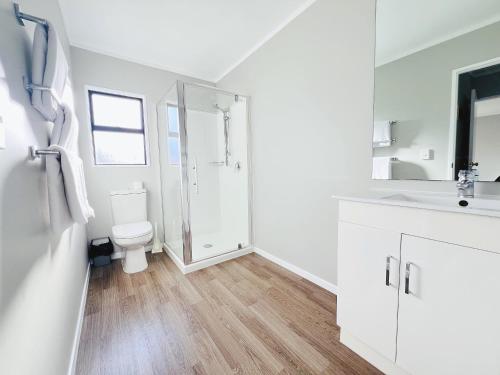 a white bathroom with a toilet and a shower at Camelot On Ulster in Hamilton