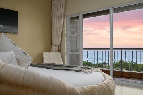 a bedroom with a bed and a view of the ocean at Umthunzi Hotel and Conference in Umtentweni