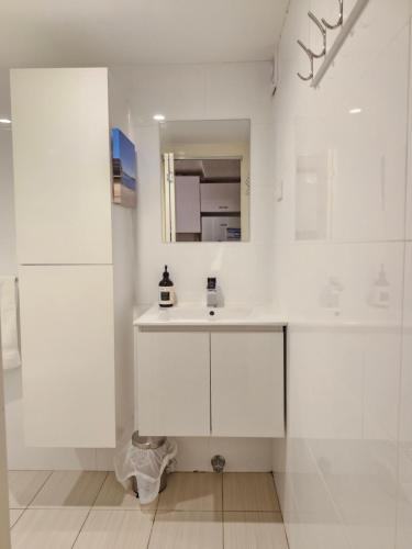 a white bathroom with a sink and a mirror at Manly Waterside in Sydney