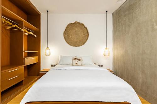 a bedroom with a white bed and a wall at SNUG Kuta in Kuta