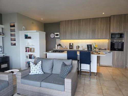 a living room with a couch and a kitchen at Amelia's by the Sea in Groot Brak Rivier