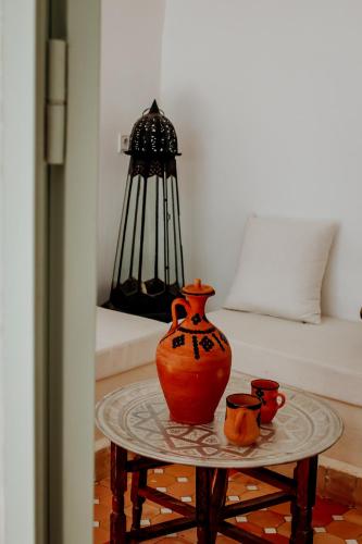 an orange vase on a table next to a bed at Dar Inara in Marrakech